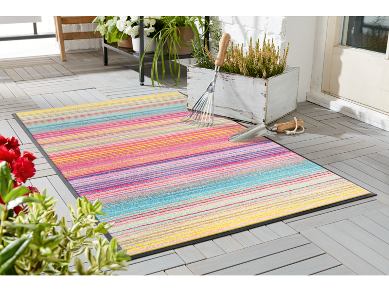 Fußmatte mit bunten Streifen im Gartenbereich