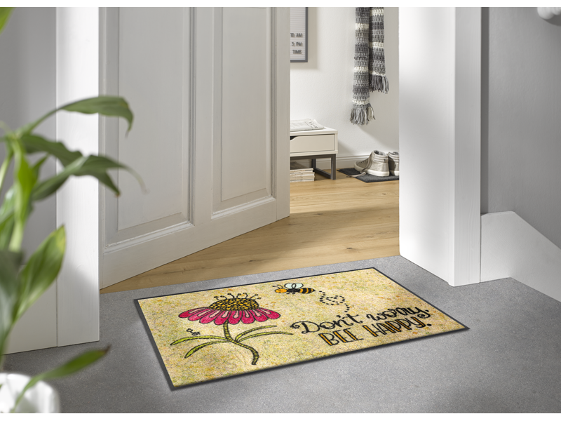 Fußmatte mit Blume und Biene und Schriftzug "don´t worry, be happy" vor der Tür