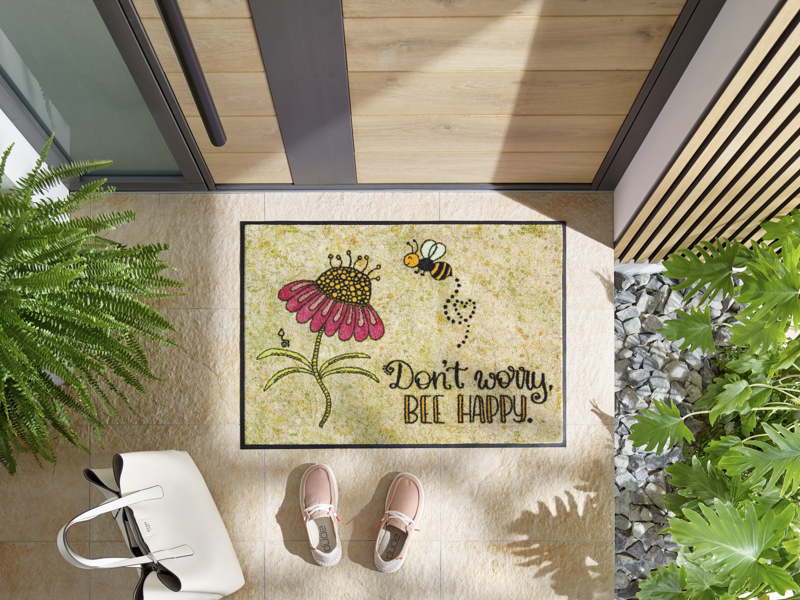 Fußmatte mit Blume und Biene und Schriftzug "don´t worry, be happy" vor der Tür