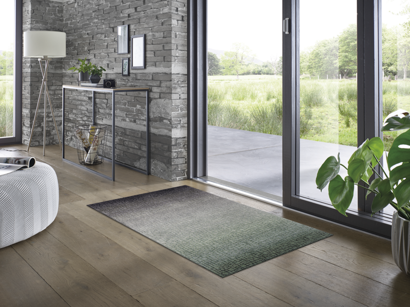 Fußmatte mit grün-schwarzer und dezenter Musterung vor der Tür