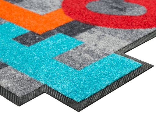 Eckansicht der Fußmatte in spezieller Form mit bunten, tanzenden Buchstaben "WELCOME"