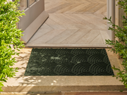 dunkelgrüne Fußmatte mit 3D-Struktur im Außenbereich vor der Tür liegend