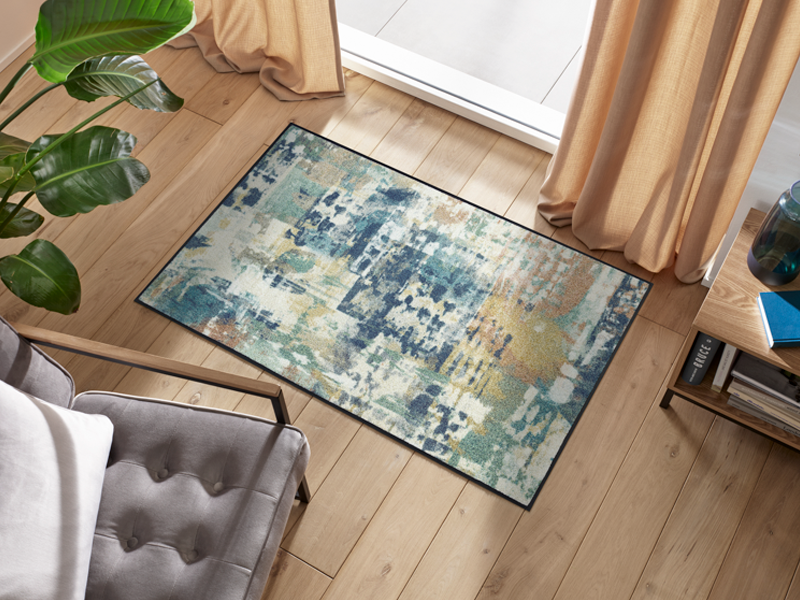 Fußmatte mit blau, grünem abstraktem Muster vor dem Fenster