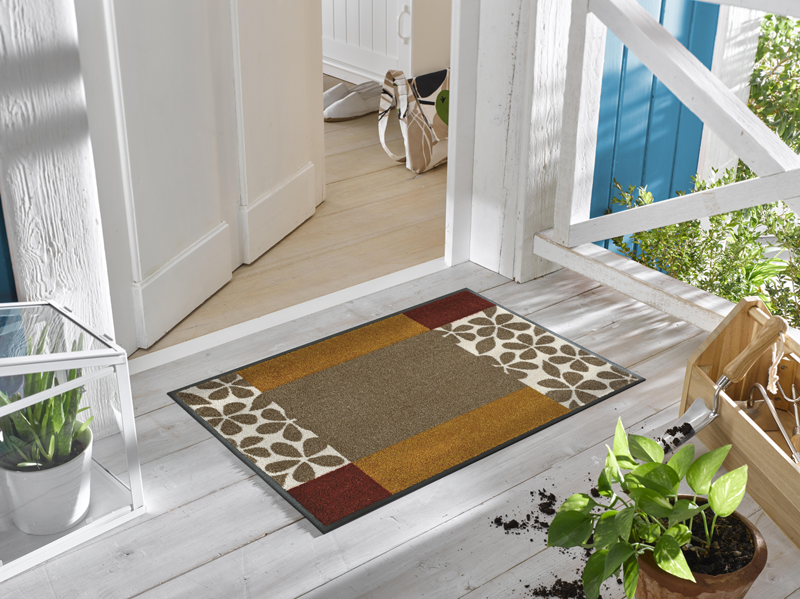 rot-braunfarbene Fußmatte mit floralem Design vor der Haustür