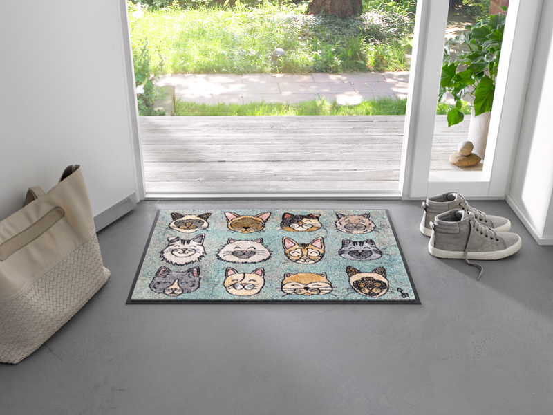 Fußmatte mit Katzenköpfen vor der Tür