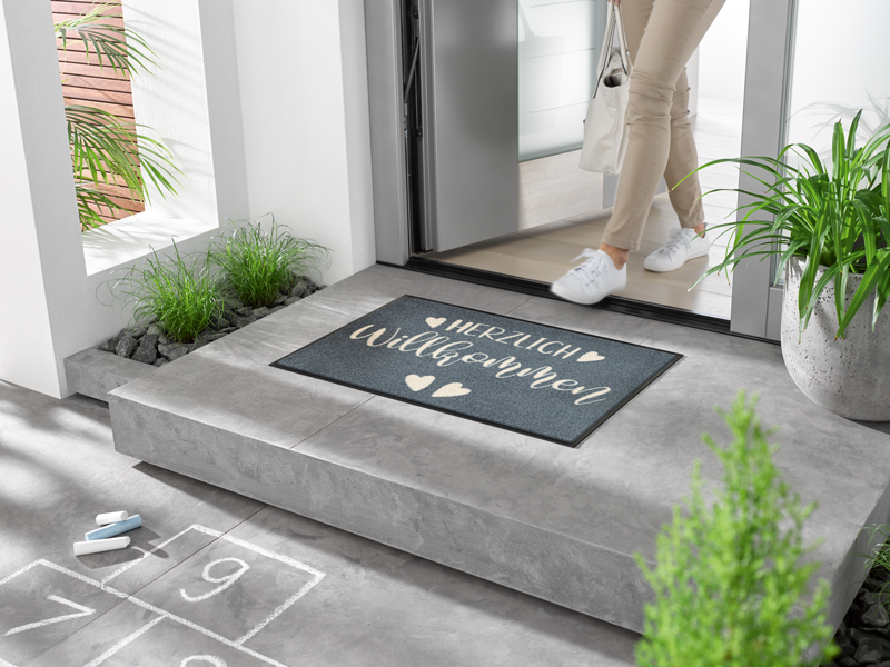 Fußmatte "Herzensgruss" mit Schrift Herzlich Willkommen" und Herzen in grau, weiß vor der Tür