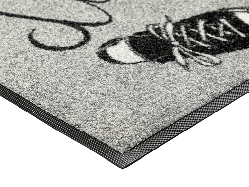 Eckansicht der grauen Fußmatte mit Schriftzug "Hier wohnen du & ich" und 2 Schuhen