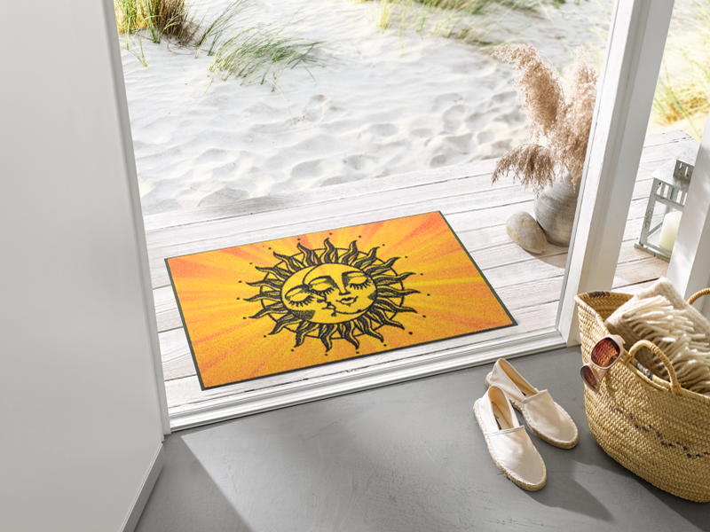 Fußmatte mit Sonnen- und Mondgesicht vor der Tür