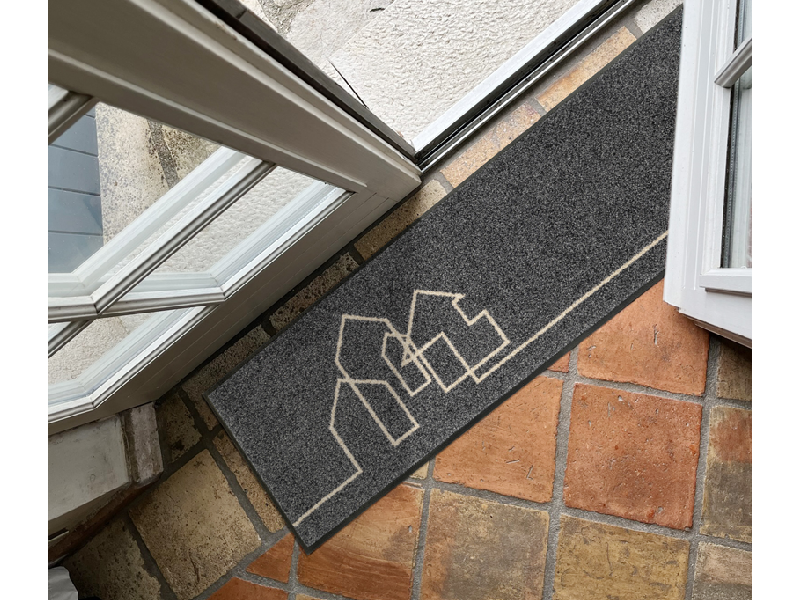 Fußmatte in grau mit gezeichneten Häusermotiven vor der Tür