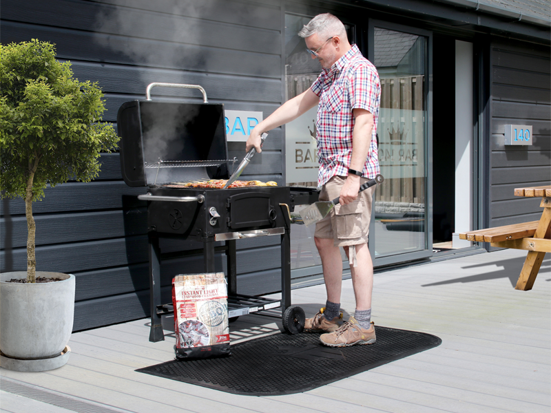 schwarze halbrunde BBQ-Matte mit Logo Matsmiths vor dem Griller
