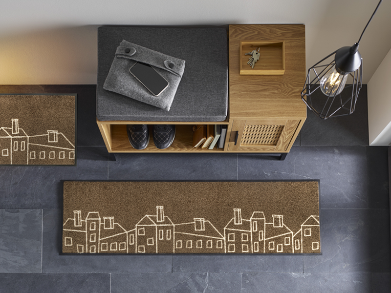 braune Fußmatte mit Häusern darauf in der Garderobe