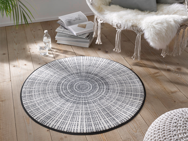 runde Fußmatte mit grau, weißer Linienstruktur im Wohnzimmer