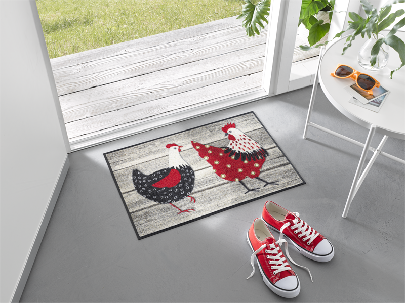 Fußmatte mit rot/weiß/schwarzen Hühnern im Eingangsbereich