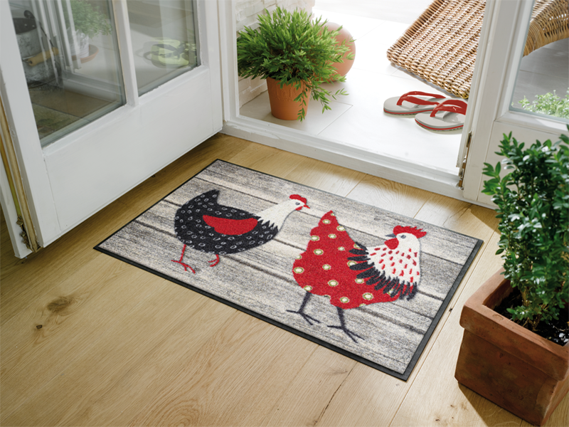Fußmatte mit rot/weiß/schwarzen Hühnern im Eingangsbereich