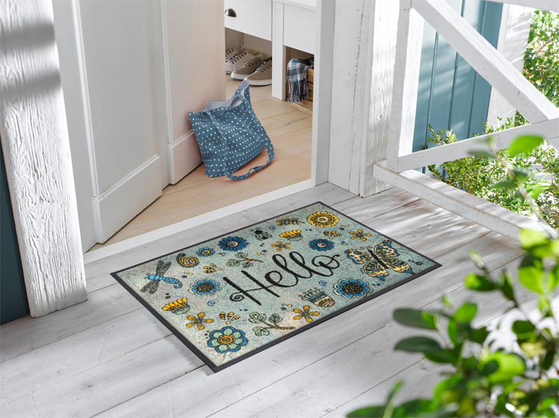 Fußmatte mit Blütenmotiven, Schmetterling, Libelle und Schriftzug "Hello" vor der Eingangstür