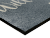 Eckansicht der Fußmatte "Herzensgruss hoch" in grau mit Text " HERZLICH Willkommen" und Herzen in weiß