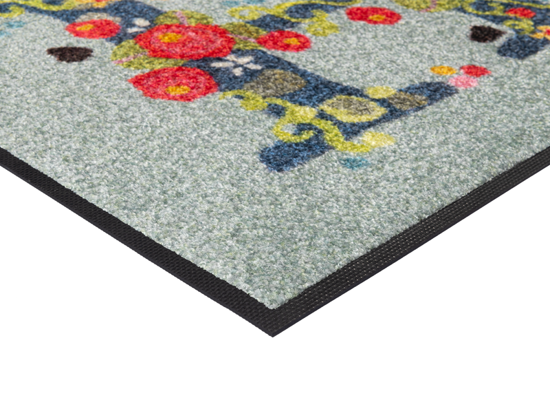 Eckansicht der Fußmatte mit Schriftzug "HI" mit Blumen geschmückt