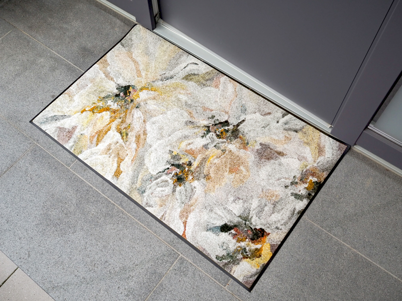 Fußmatte mit dezentem Blütendesign vor der Tür