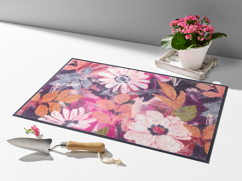 Fußmatte mit pink, rosaroten Blumen auf dem Boden liegend