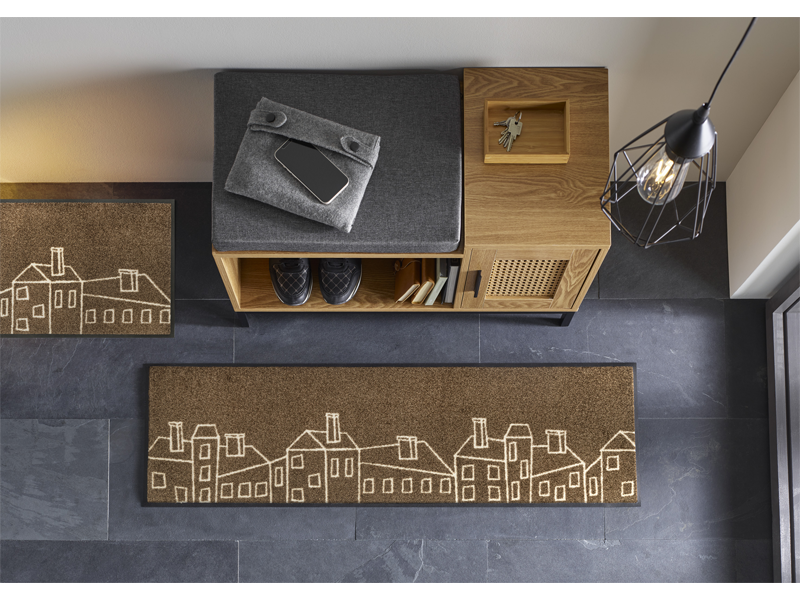 Fußmatte in braun mit gezeichneten Häusermotiven vor der Garderobe