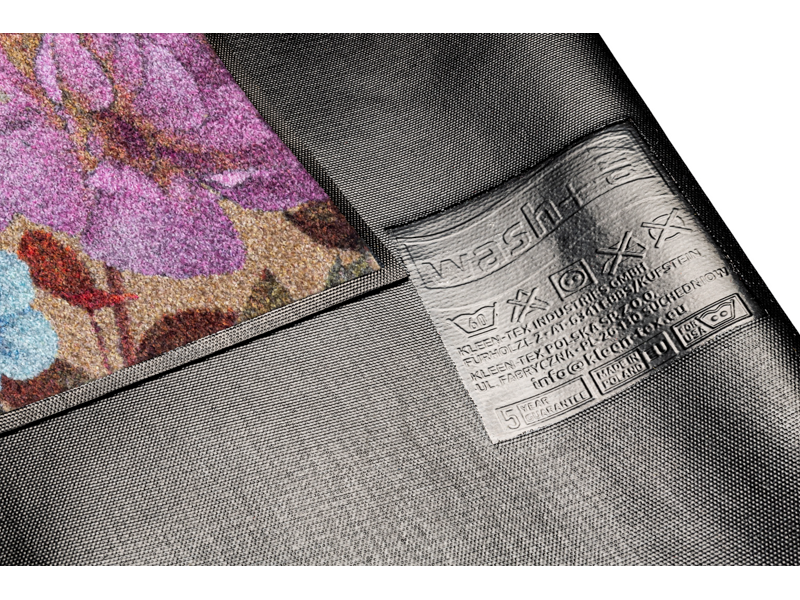 Rückenansicht der Fußmatte in schwarz mit buntem, violettem Blumenmotiv
