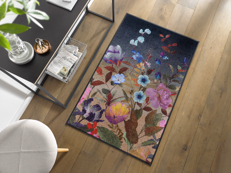 Fußmatte in schwarz mit buntem, violettem Blumenmotiv im Eingangsbereich