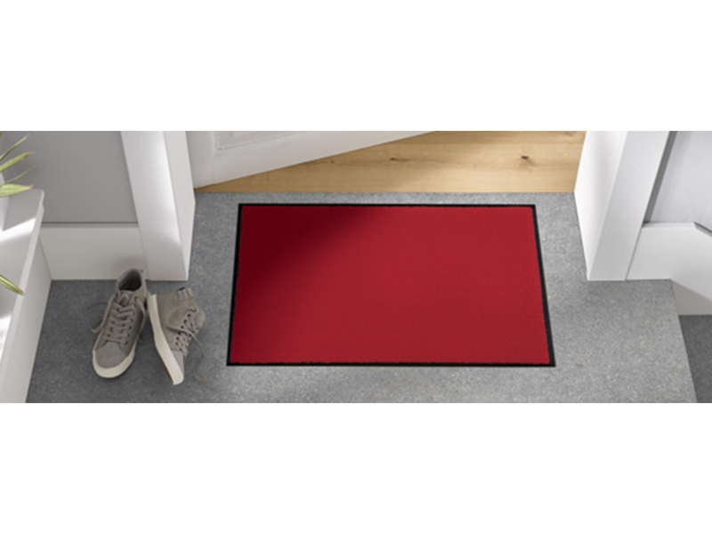rote Fußmatte auf dem Fußboden vor der Tür