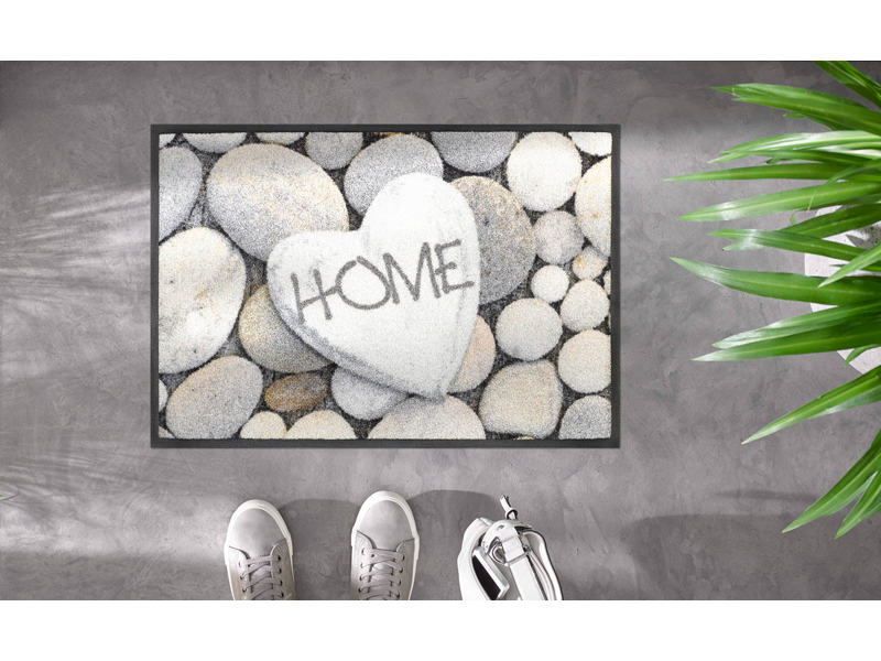 Fußmatte mit Steinen und Schrift "HOME" auf dem Boden