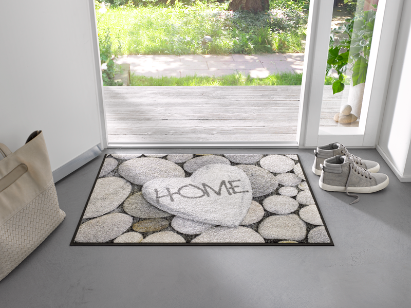 Fußmatte mit Steinen und Schrift "HOME" im Eingangsbereich