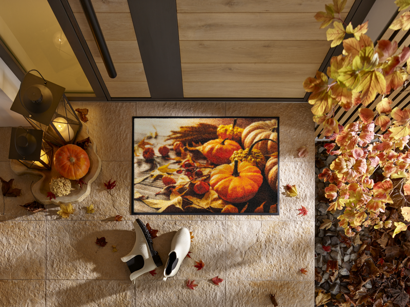 Fußmatte mit herbstlichem Kürbismotiv vor der Tür