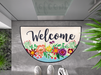 halbrunde Fußmatte mit Blumen und Schriftzug "Welcome" vor der Tür