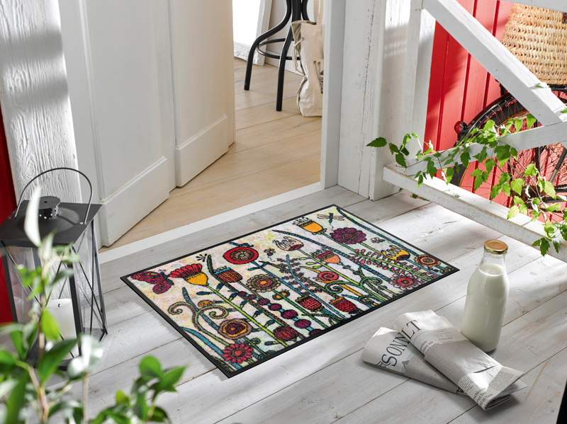 Fußmatte mit gemalenen Blumenmotiven vor der Tür