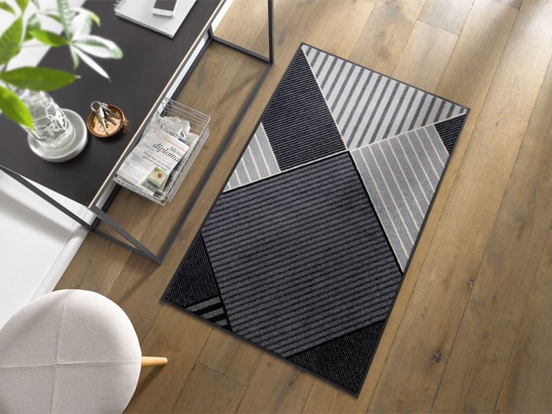 Fußmatte mit grau-schwarzen Streifen in geometrischen Formen im Eingangsbereich