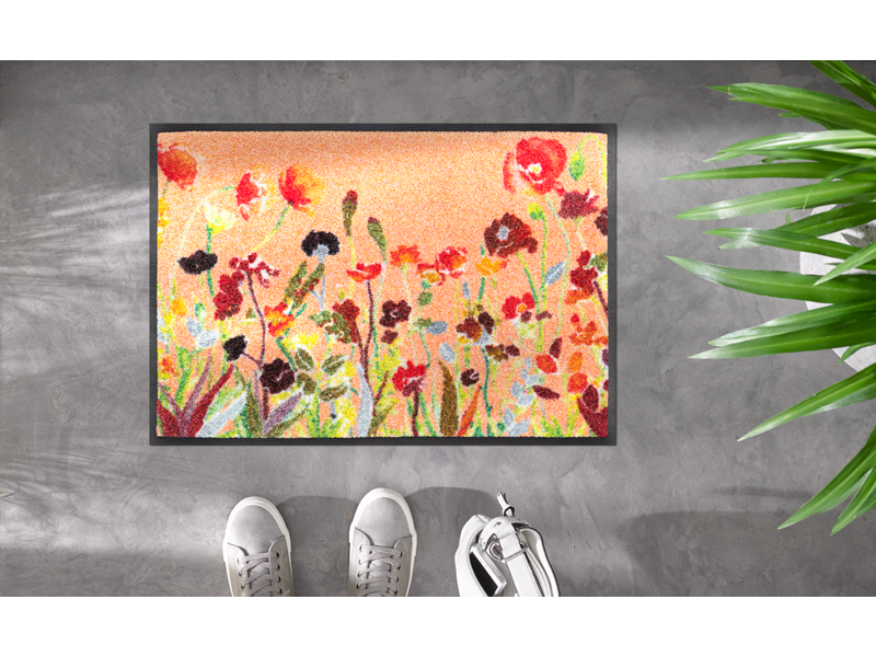 Fußmatte in Rottönen mit farbenfrohen Blumen auf dem Boden