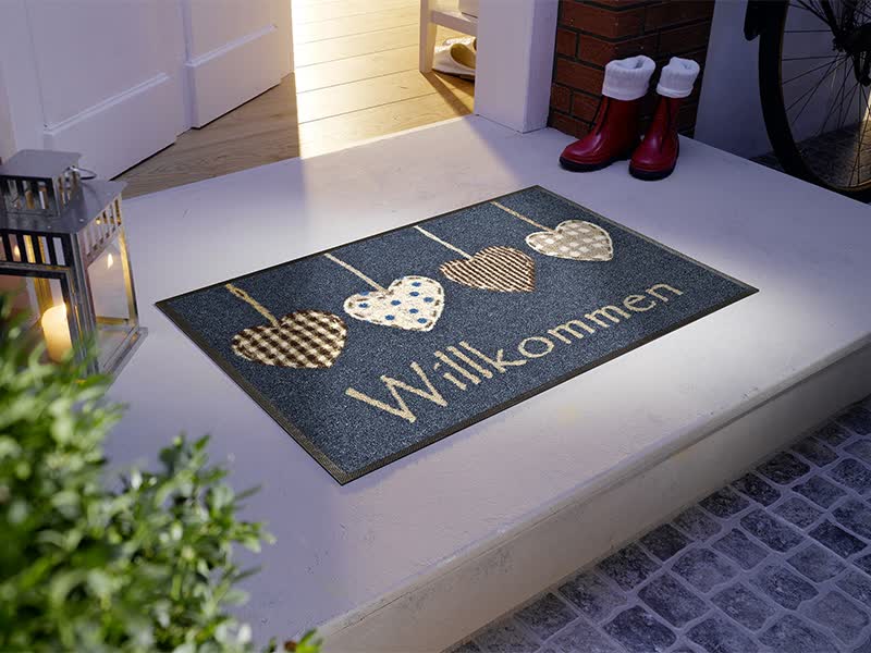 Fußmatte mit Herzen und Schrift "Willkommen" vor der Eingangstür